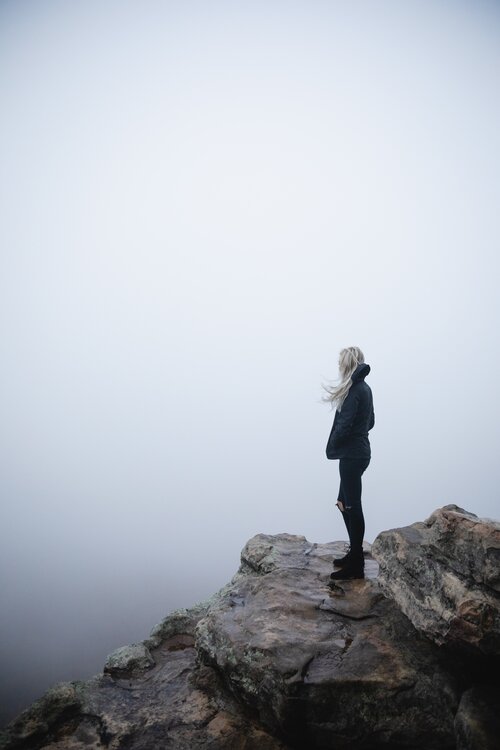 girl stood on top of rocks with misty background