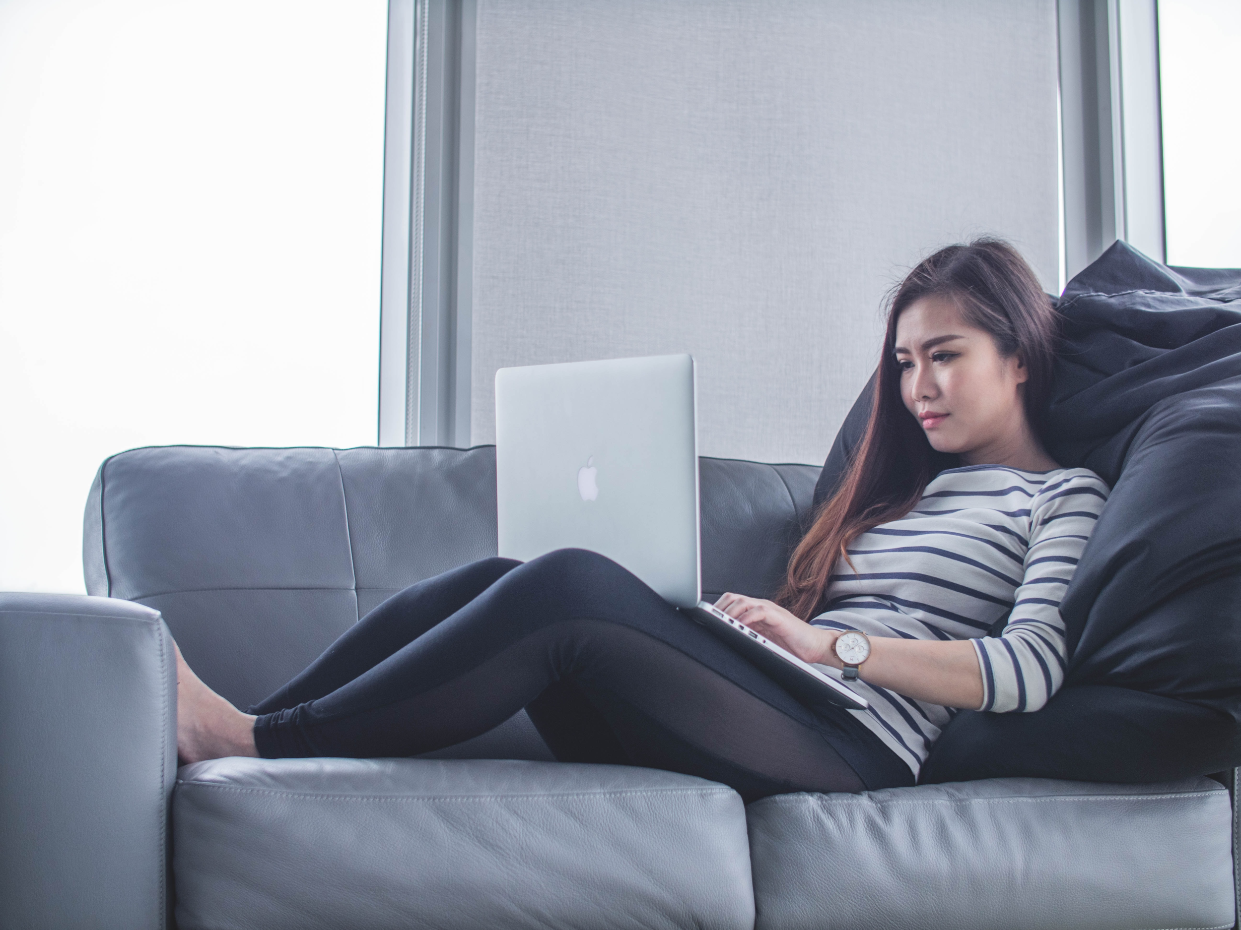 asian lady relaxing on sofa with her laptop